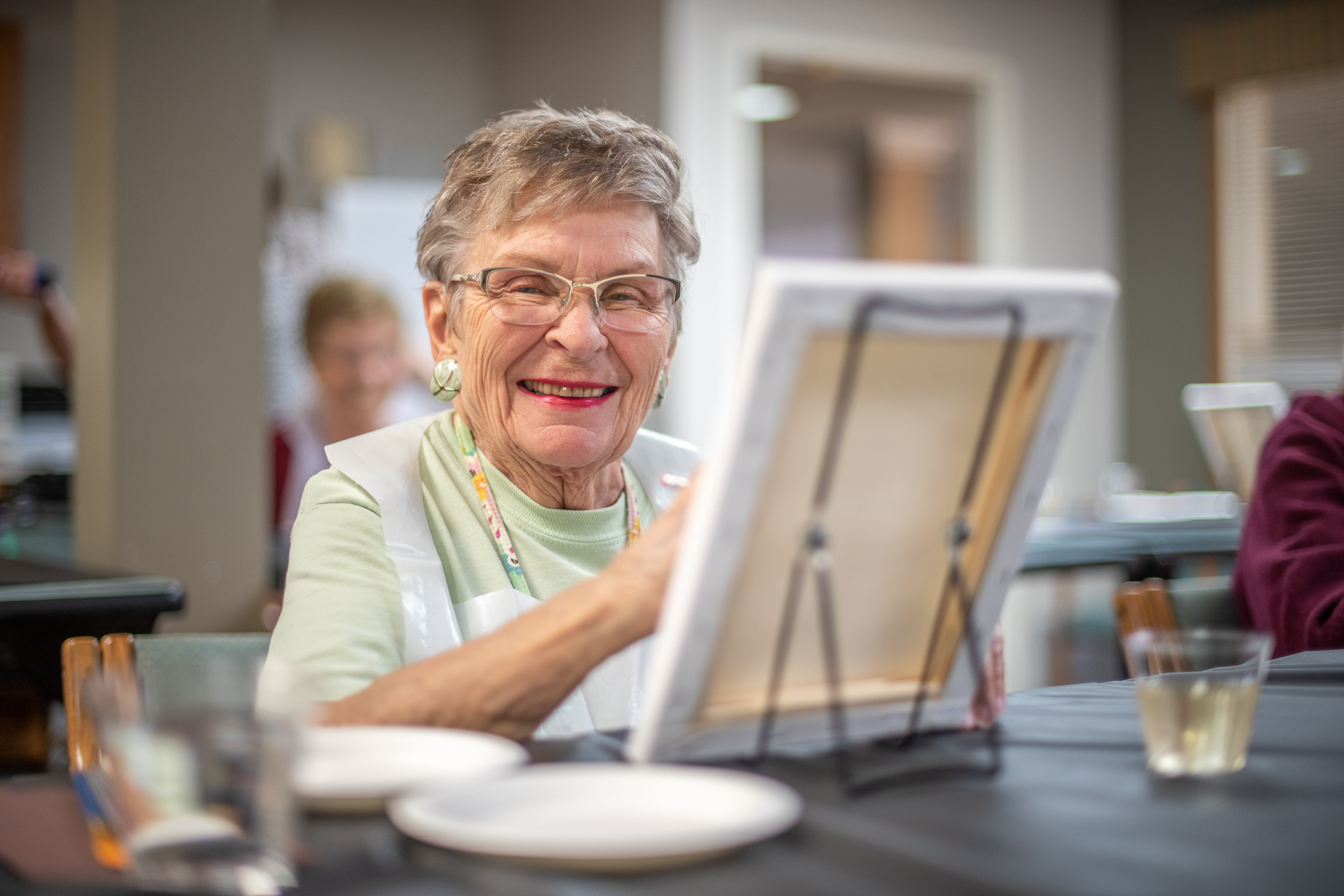Older woman smiling while painting - skilled nursing homes near me