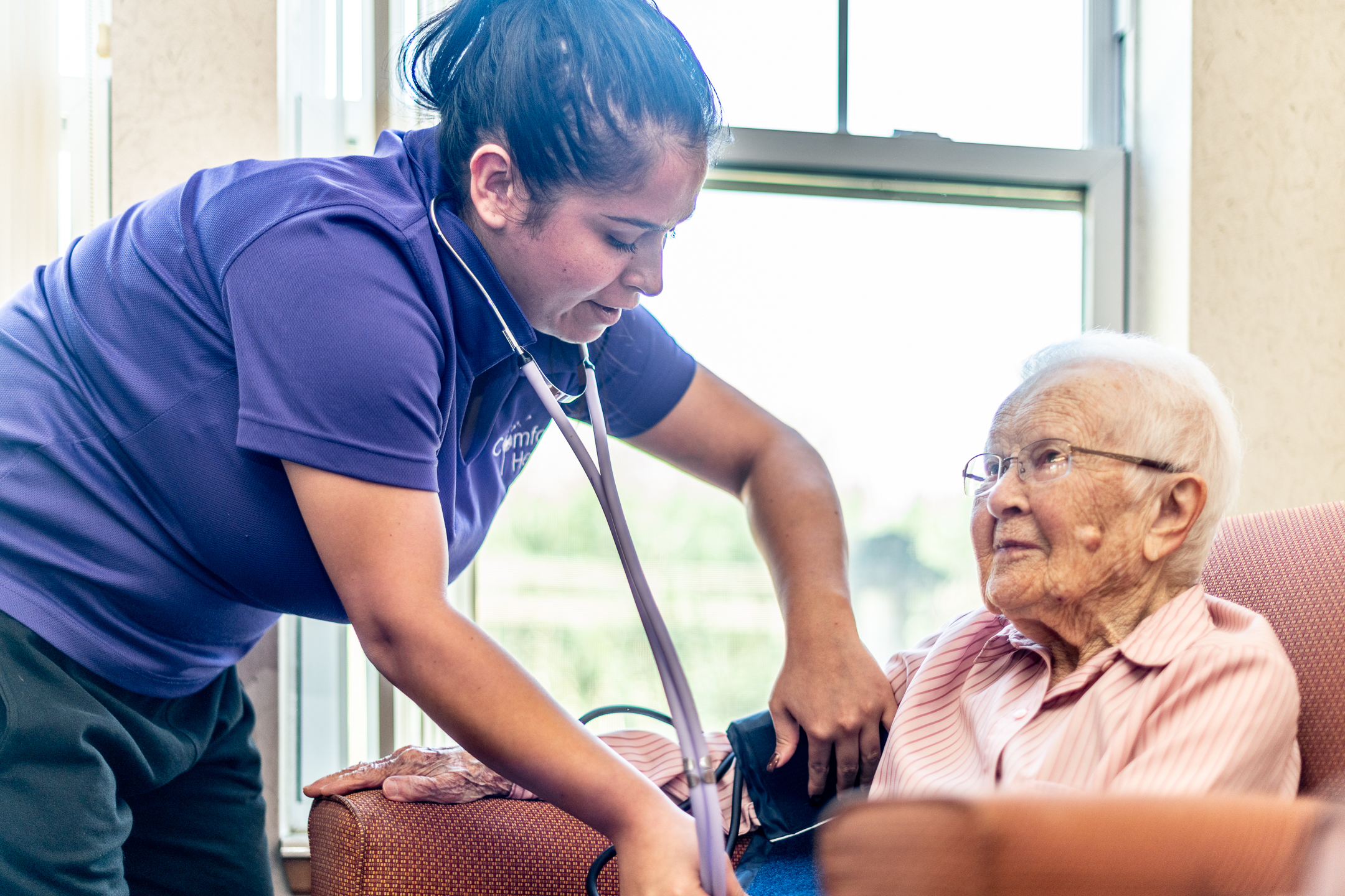 Nurse checking a senior woman's blood pressure - assisted living services