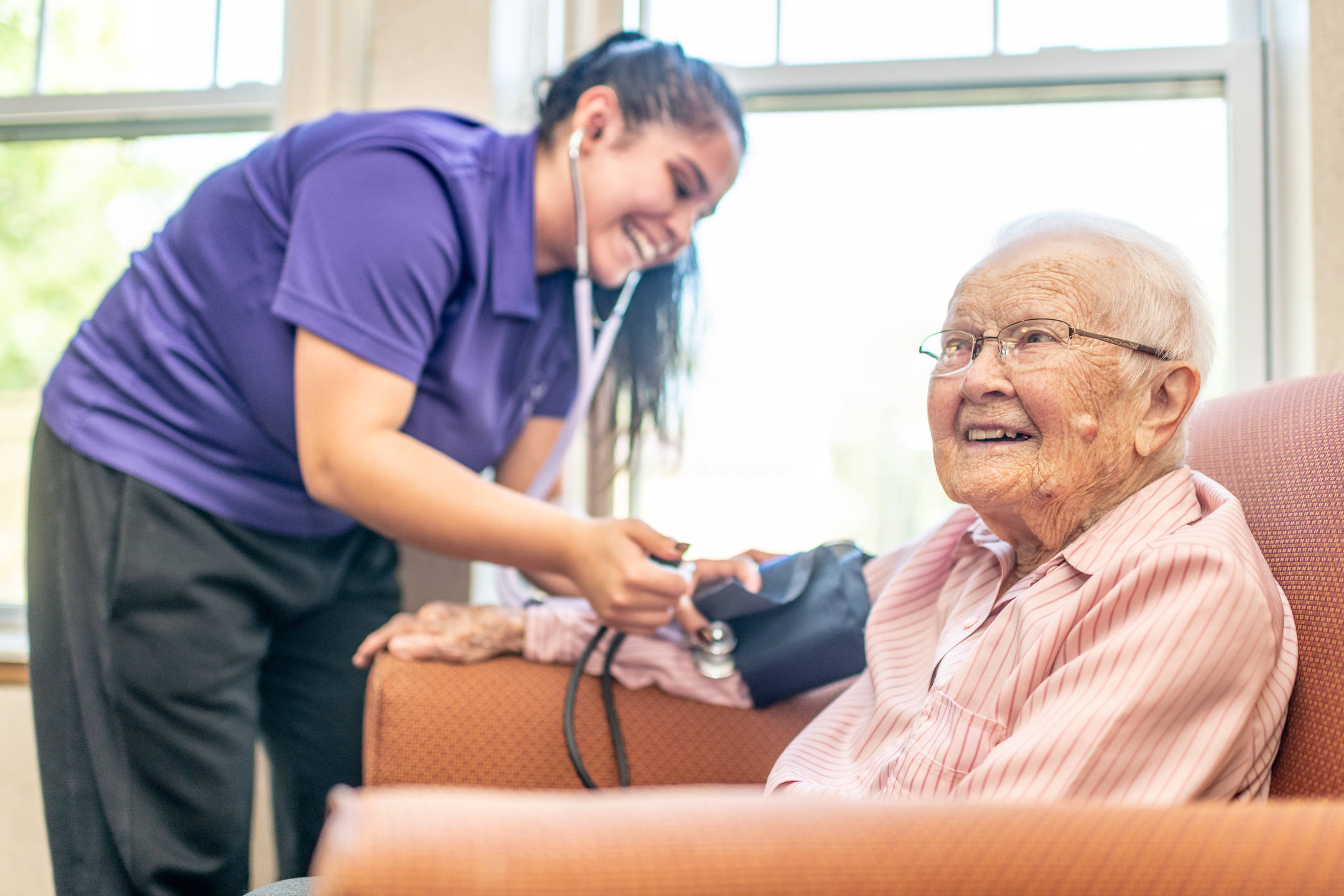 DSC5831 Caregiver helping a smiling senior with mobility support - best nursing homes near me