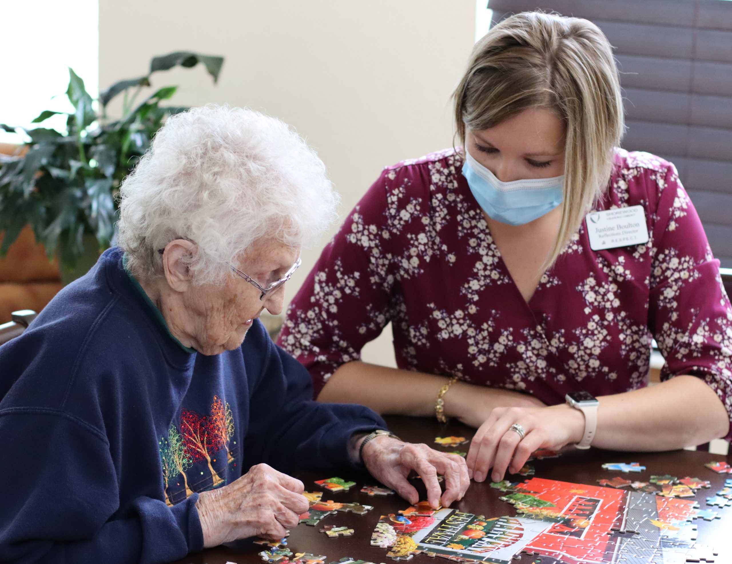Older adults doing crafts and puzzles in a bright community room - 55 community near me
