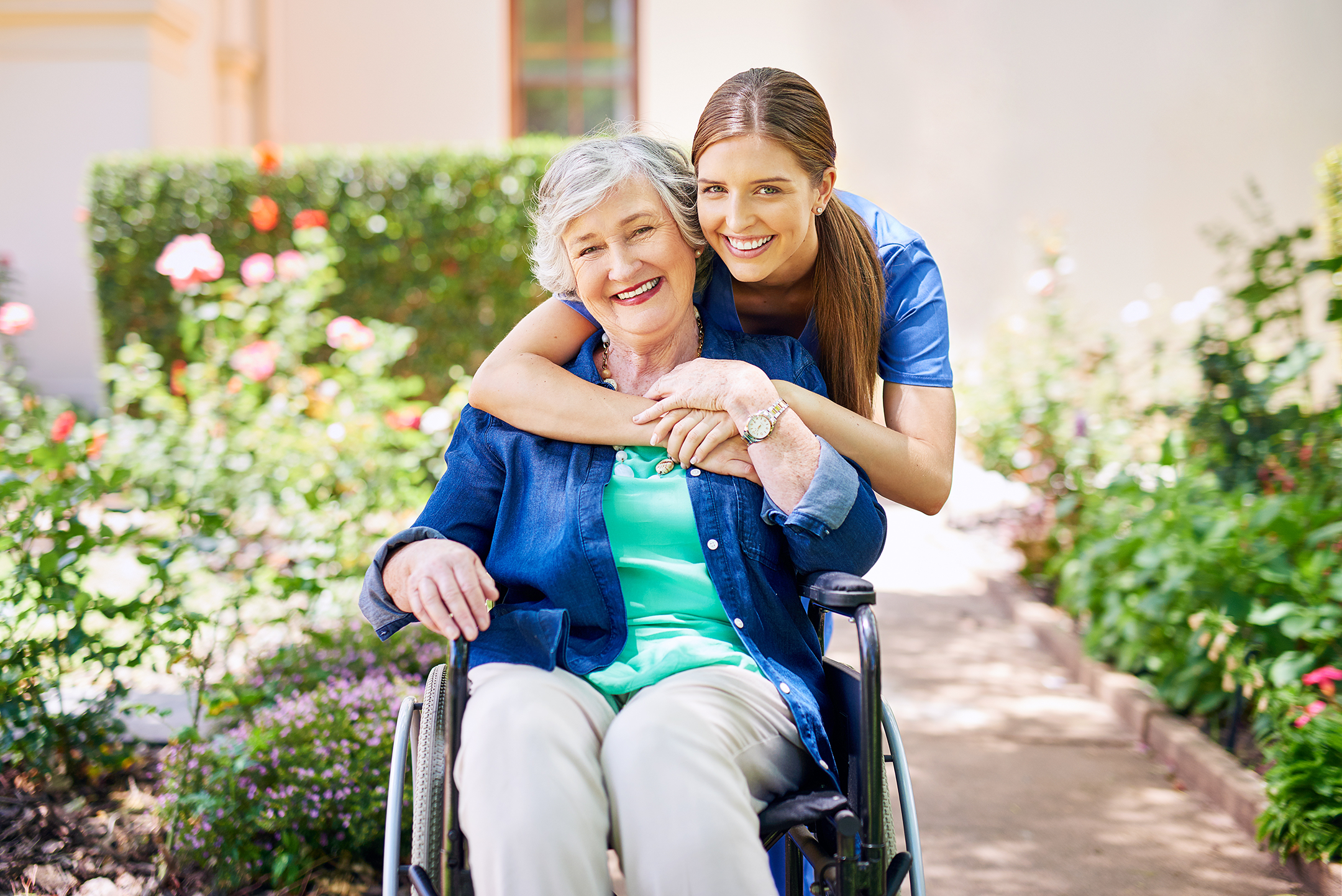 Young caregiver and elderly woman smiling together outdoors - senior living near me