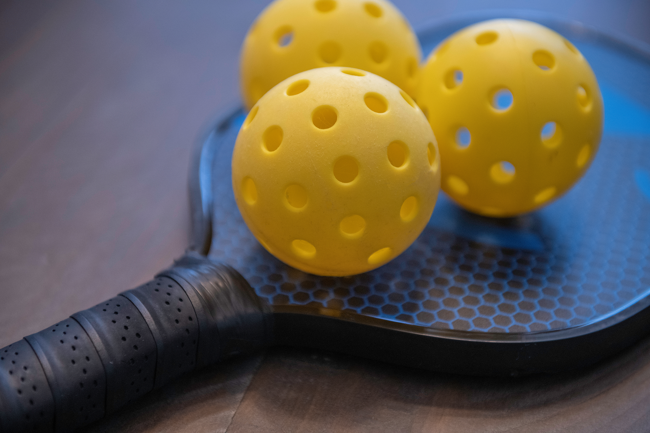 Close-up of two yellow pickleball paddles and balls on a court - memory care